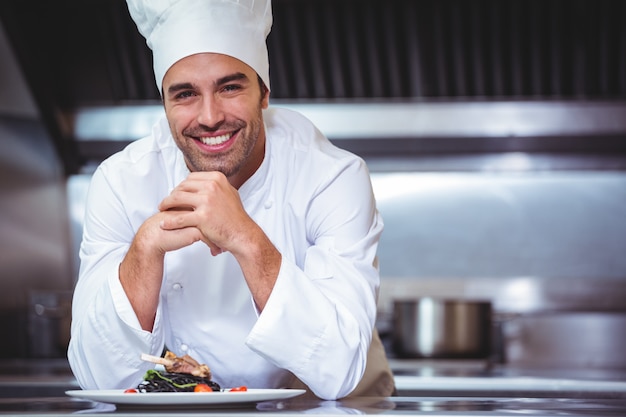 Chef, der auf der Theke mit einem Teller sich lehnt