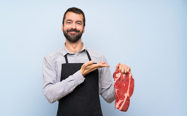 Chef, der ein rohes Fleisch darstellt eine Idee beim Schauen lächelnd in Richtung hält