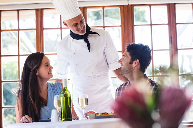 Chef, der mit Paaren am Restaurant spricht