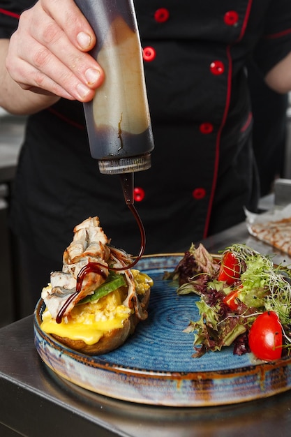 Foto chef derramando molho unagi na torrada torrada de pão de trigo sarraceno com ovo mexido um abacate fatiado uma enguia tomate e alface menu dietético postura plana