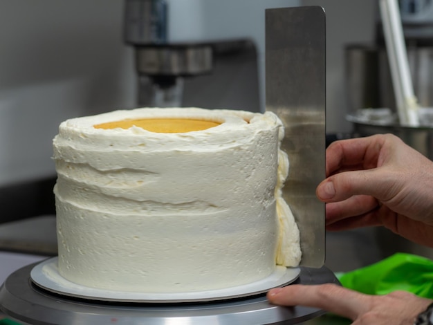 Chef diseñador de repostería confeccionando un pastel helado de 3 pisos relleno de fresas y crema de mantequilla batida