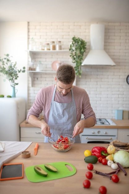 Chef. Ein Mann, der einen gesunden und nahrhaften Salat zum Abendessen mischt