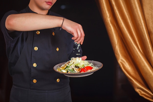 Chef de ensalada César con queso parmesano.