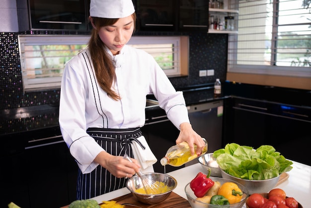 Chef con ensaladera Chef haciendo crema para aderezo de ensaladas La cocina está llena de ingredientes alimenticios