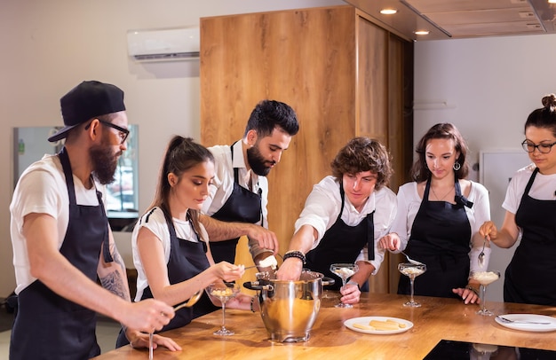 Chef enseñando a los aprendices cómo hacer helado Cocinar un delicioso postre helado hecho de chocolate y vainilla en un recipiente de vidrio