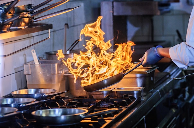 Chef está revolviendo verduras en wok a fuego abierto