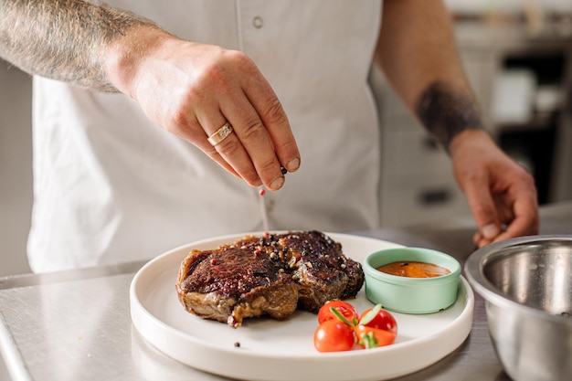 Chef está rociando condimentos en el bistec Cerrar