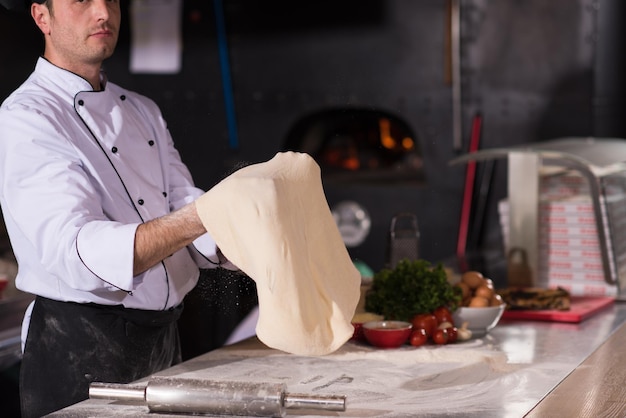 Chef experto preparando masa para pizza rodando con las manos y vomitando