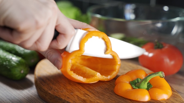 Chef fatiando legumes frescos na cozinha. Mão de homem cortando laranja, pimenta grande e fresca na cozinha