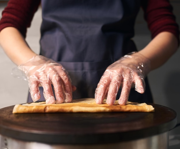 Chef fazendo crepe recheado, enrole o crepe no fogão quente. Processo de cozimento profissional passo a passo. Detalhado. Vista frontal.