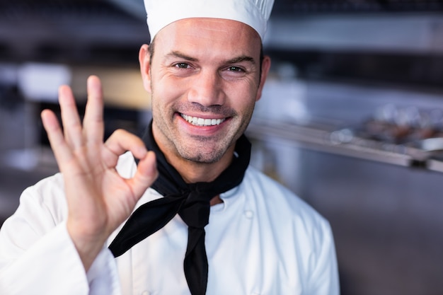 Foto chef feliz fazendo sinal de ok na cozinha comercial