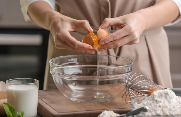 Chef femenina haciendo masa en un tazón de vidrio en la mesa de la cocina