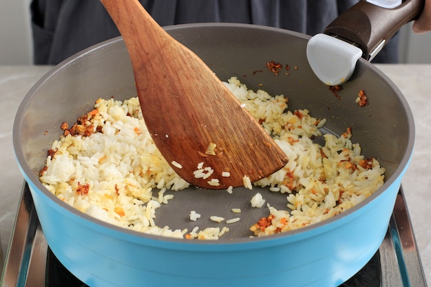 Chef feminina fazendo arroz frito na frigideira, passo a passo na cozinha