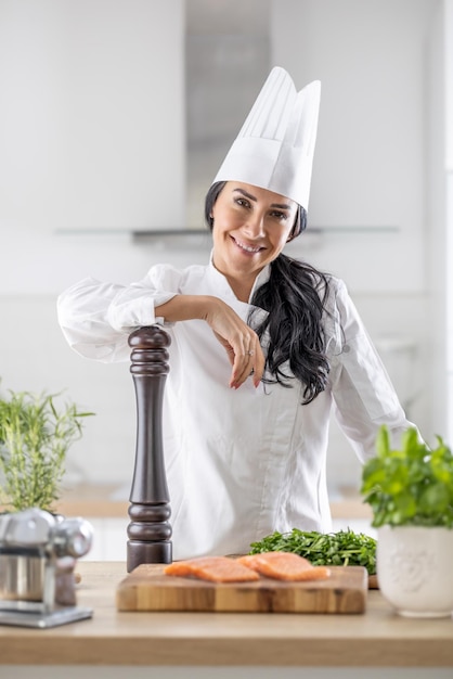 Chef feminina profissional confia no moedor de pimenta com ingredientes para cozinhar na frente dela