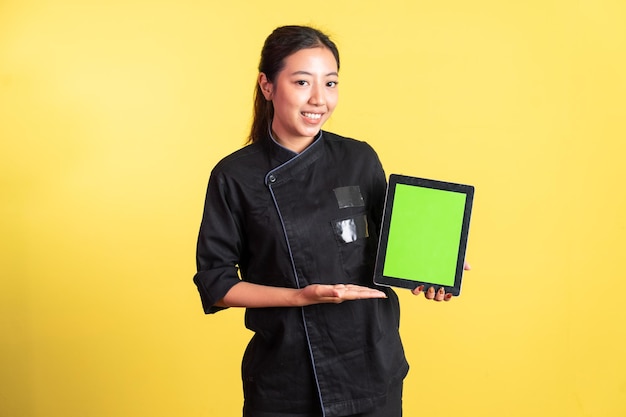 Chef feminina sorridente mostrando a tela do bloco em branco com a mão apresentando algo no fundo isolado
