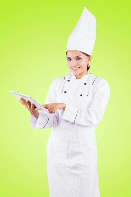 Chef feminino jovem usando um tablet no estúdio