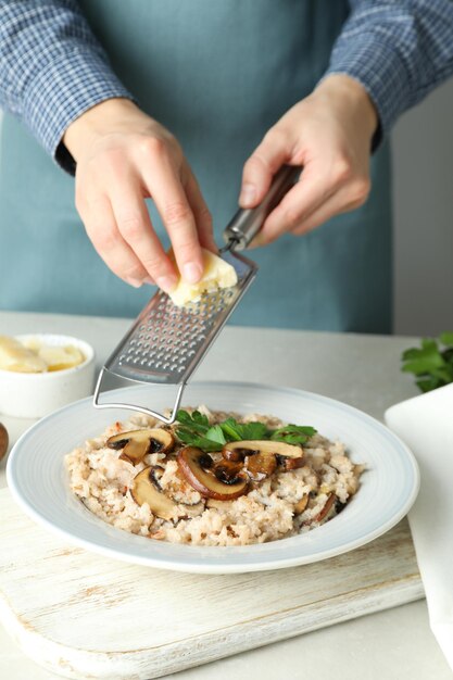 Foto chef feminino ralar queijo no risoto com cogumelos