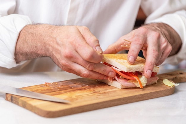 Chef finaliza sandwich con jamón y ensalada