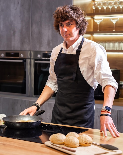 Chef fritando pães de hambúrguer para jantar no espaço da cópia da cozinha