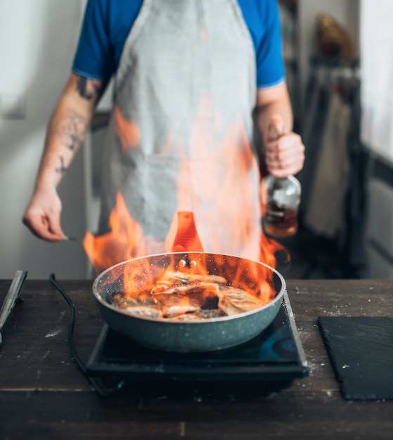 Chef gegen Pfanne mit Feuer, Fisch kochen