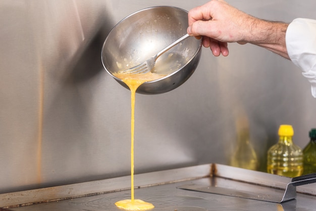 Foto chef gießt omelettmischung in eine heiße pfanne