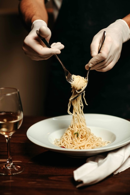 Chef gira espaguetis con tenedor y cuchara