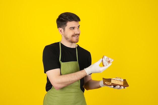 Chef guapo sonriente mostrando una rebanada de pastel en amarillo.