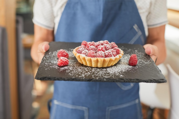 Chef hält Himbeerkuchen im Café