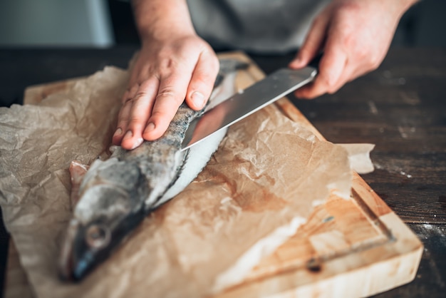 Chef Hände mit Messer schneiden Fisch auf Schneidebrett