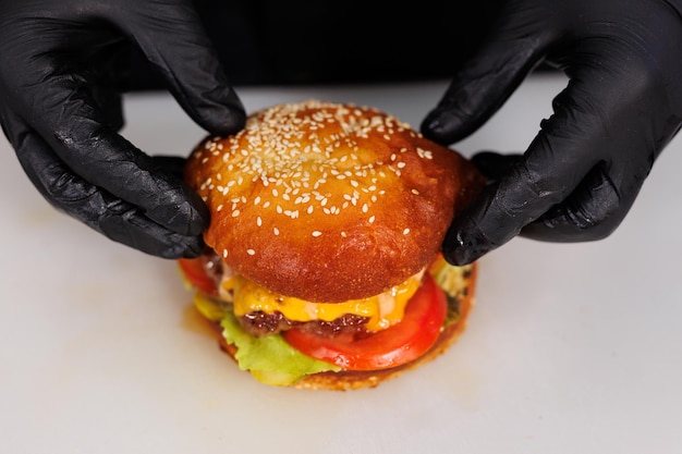 Foto chef y hamburguesa de queso con verduras y carne en la cocina del restaurante
