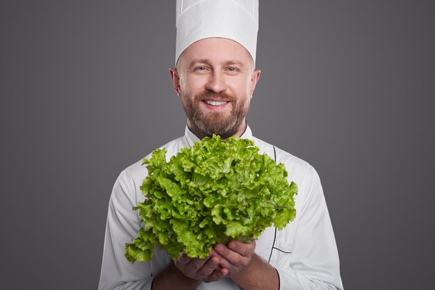 Chef hombre alegre con lechuga fresca