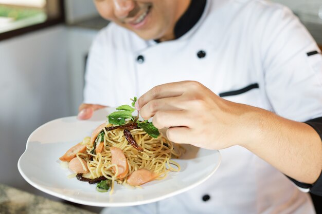 Chef hombre asiático cocinando comida en restaurante