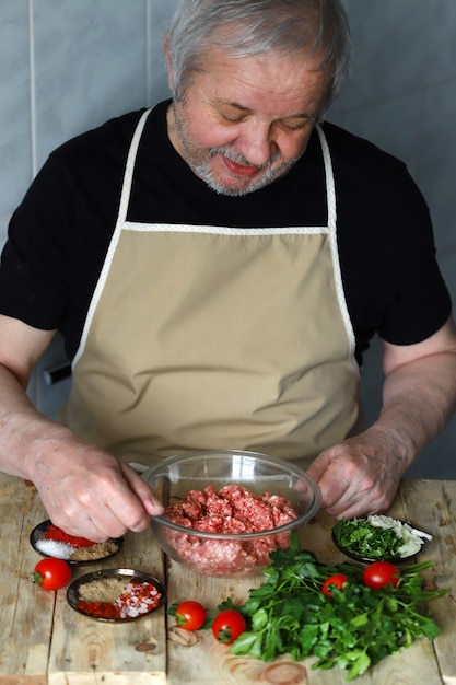 Chef hombre carga especias en un plato de carne picada