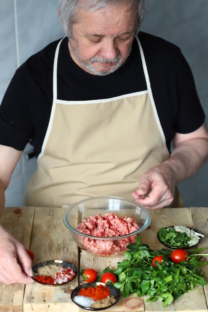 Chef hombre carga especias en un plato de carne picada