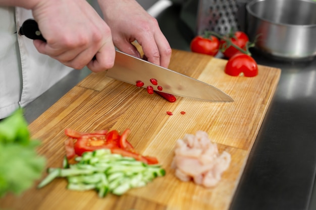 Chef hombre cortando chiles en la mesa