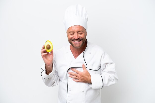 Chef hombre sosteniendo un aguacate aislado sobre fondo blanco sonriendo mucho