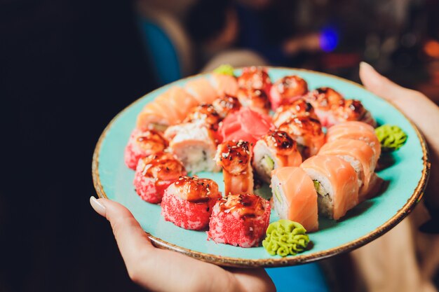 Foto chef in der hotel- oder restaurantküche, die geschmackvolle rollen mit japanischer mayonnaise in der flasche verziert. sushi-set vorbereiten. nur hände.