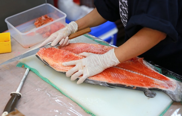 Chef japonés en restaurante rebanar pescado crudo para sushi de salmón.