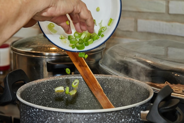 Chef joga alho-poró em panela no fogão a gás