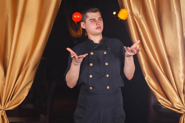 Chef joga pimentões e tomates. Foto engraçada. Copie o espaço. Retrato de um cozinheiro no trabalho.