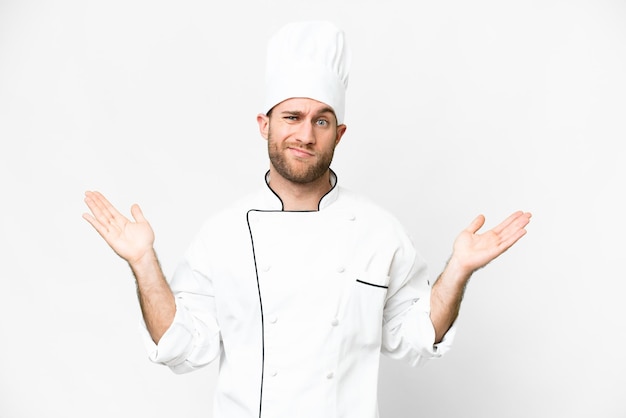 Chef joven rubio sobre fondo blanco aislado que tiene dudas mientras levanta las manos