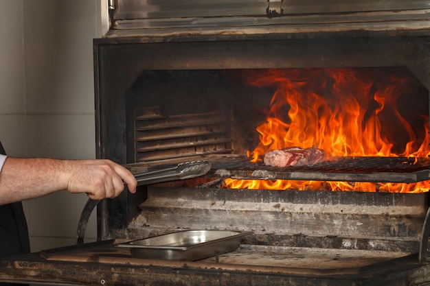 Chef macht Rindersteak auf offenem Feuer im Restaurant