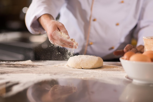 chef manos preparando masa para pizza en primer plano de mesa rociada con harina