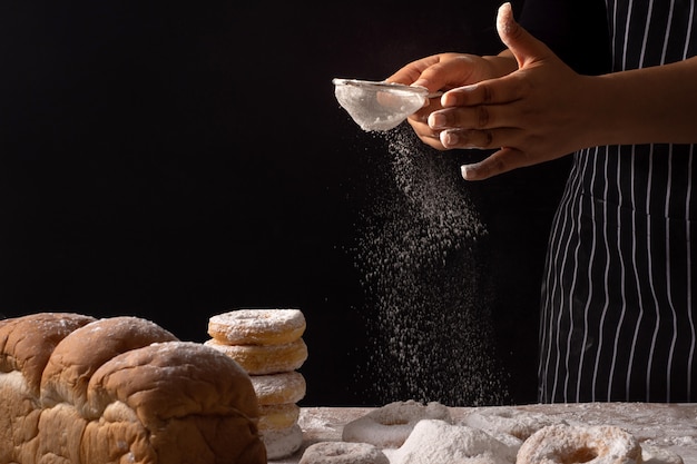 Foto chef manos rociadas preparando masa de pan y rosquillas