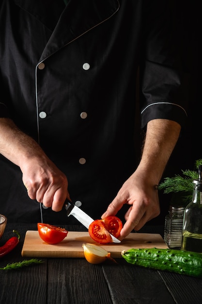 Chef mãos com faca cortando tomates vermelhos frescos para salada