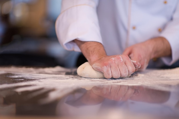 Chef mãos preparando massa para pizza polvilhada com farinha mesa closeup