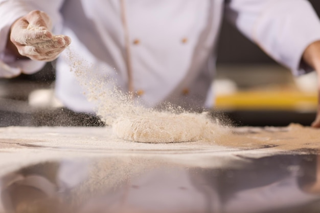 chef mãos preparando massa para pizza polvilhada com farinha mesa closeup