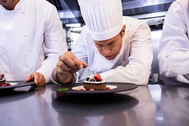 Chef masculino adornar plato de postre en mostrador