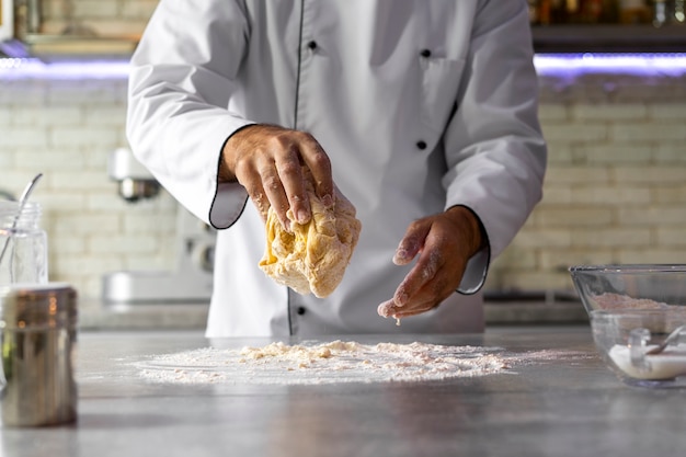 Foto chef masculino en la cocina amasando masa