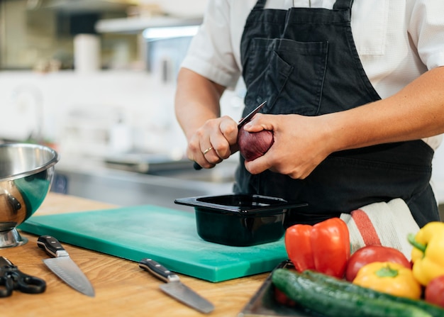 Foto chef masculino com avental cortando legumes